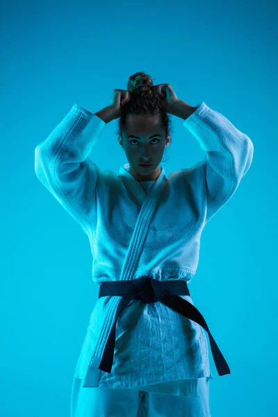 Porträt einer professionellen Judoistin isoliert auf blauem Studiohintergrund in Neonlicht. Gesunder Lebensstil, Sportkonzept. — Stockfoto