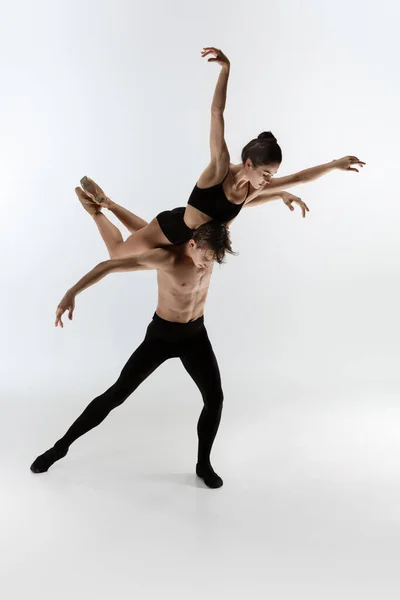 Jonge en sierlijke ballet dansers in minimale zwarte stijl geïsoleerd op witte studio achtergrond — Stockfoto