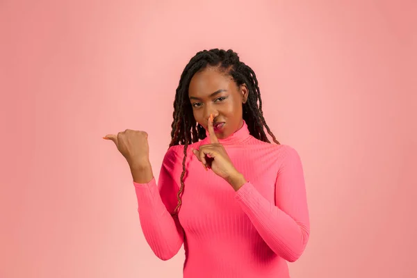 Молода афро-американка ізольована на рожевому студійному фоні, вираз обличчя. Красивий жіночий напівдовгий портрет з копійкою . — стокове фото
