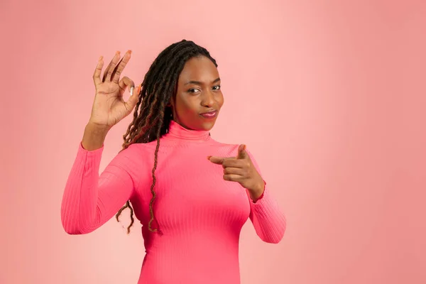 Портрет молодої афро-американки, ізольованої на рожевому студійному фоні, вираження обличчя. Красивий жіночий напівдовгий портрет з копійкою . — стокове фото