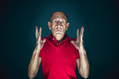 Karanlık arka planda izole edilmiş çılgın korkmuş ve şok olmuş bir adamın portresi.