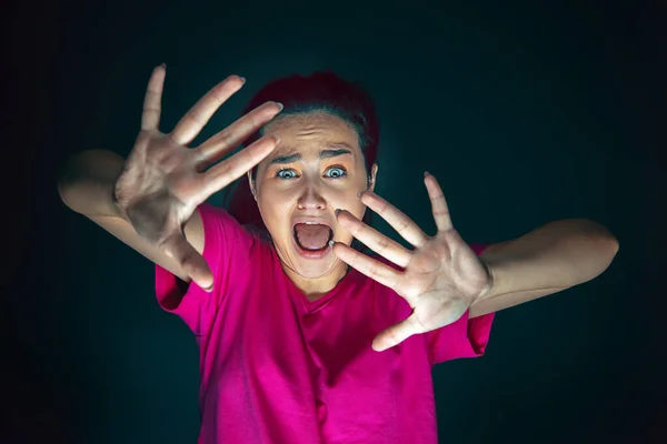 Närbild porträtt av ung galen rädd och chockad kvinna isolerad på mörk bakgrund — Stockfoto
