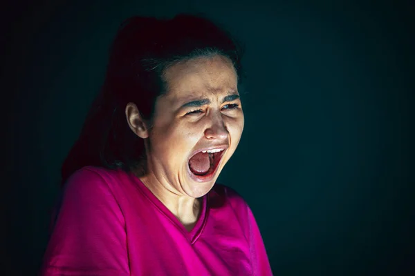 Close up portrait of young crazy scared and shocked woman isolated on dark background — Stock Photo, Image