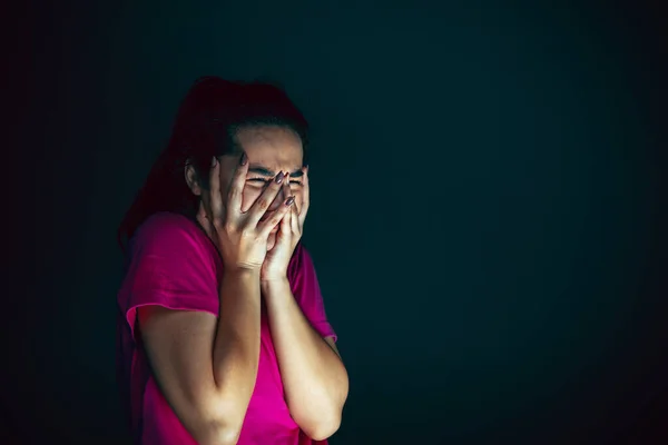 Close up portrait of young crazy scared and shocked woman isolated on dark background — Stock Photo, Image