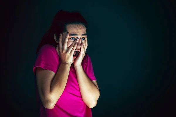 Close up portrait of young crazy scared and shocked woman isolated on dark background — Stock Photo, Image