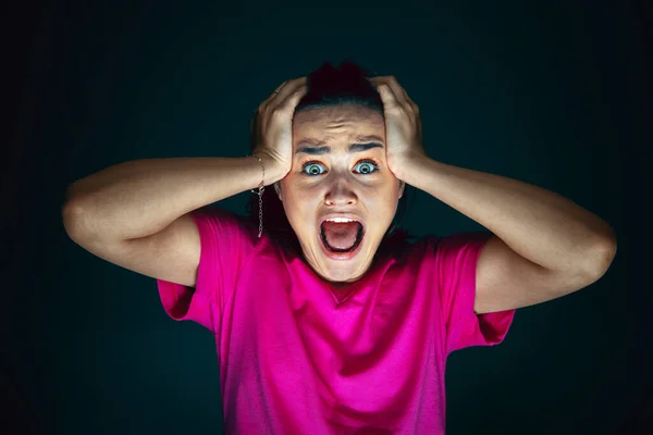 Close up portrait of young crazy scared and shocked woman isolated on dark background — Stock Photo, Image