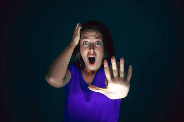 Close up portrait of young crazy scared and shocked woman isolated on dark background — Stock Photo, Image