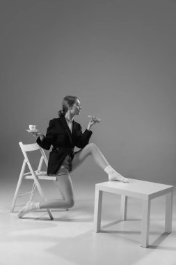 Ceket ve çorap giyen şık, genç bir bayan evde çalışıyor. Koronavirüs salgınının izolasyon nedeni sırasında moda.