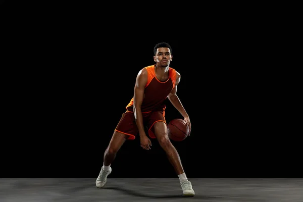 Jovem jogador de basquete africano treinando no fundo do estúdio preto. — Fotografia de Stock