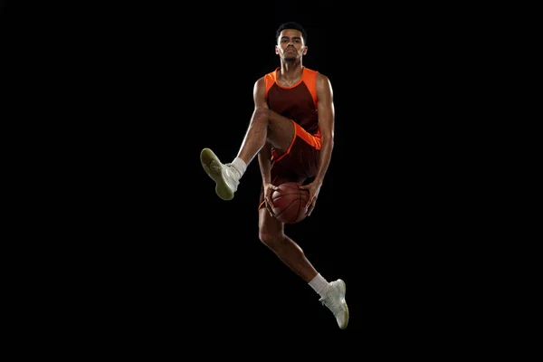 Jovem jogador de basquete africano treinando no fundo do estúdio preto. — Fotografia de Stock