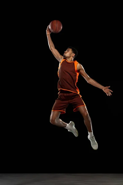 Jovem jogador de basquete africano treinando no fundo do estúdio preto. — Fotografia de Stock