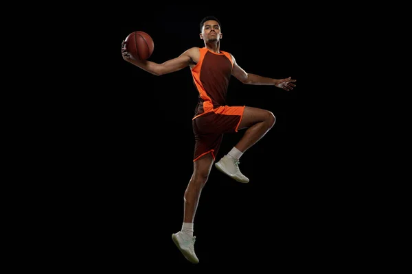 Jovem jogador de basquete africano treinando no fundo do estúdio preto. — Fotografia de Stock