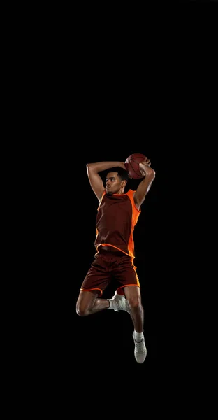 Junge afrikanische Basketballspielerin beim Training auf schwarzem Studiohintergrund. — Stockfoto