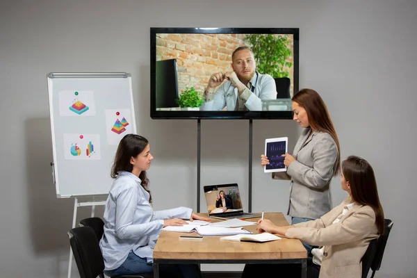 在视频会议期间与同事在办公室或客厅交谈、工作的年轻妇女 — 图库照片