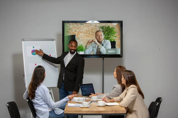 Les jeunes parlent, travaillent pendant la vidéoconférence avec des collègues au bureau ou dans le salon — Photo