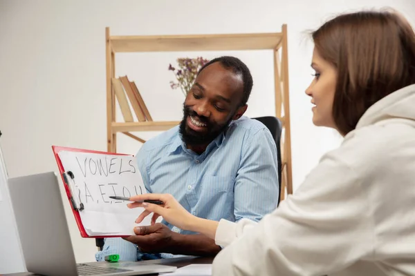 English courses at home. Smiling man teaches student in interior of living room