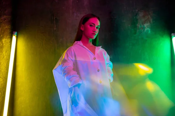 Kaukaski kobieta inclusive model pozowanie na studio tło w neon światło — Zdjęcie stockowe
