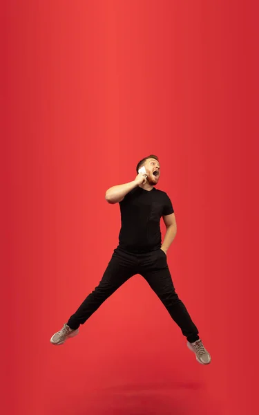 Retrato de longitud completa de hombre de salto alto de éxito joven gesto aislado sobre fondo de estudio rojo — Foto de Stock