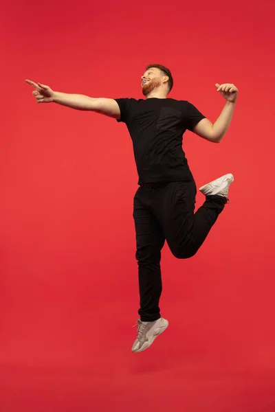 Retrato de longitud completa de hombre de salto alto de éxito joven gesto aislado sobre fondo de estudio rojo —  Fotos de Stock