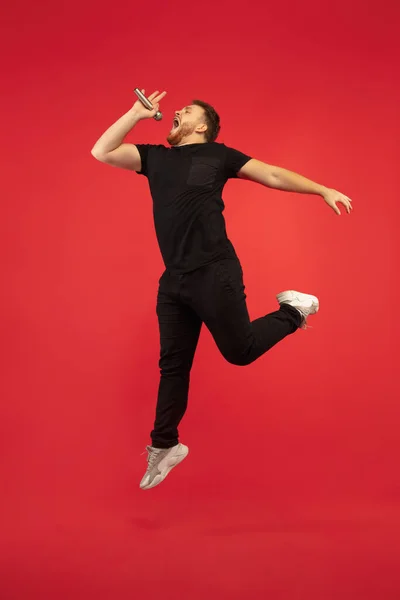 Retrato de longitud completa de hombre de salto alto de éxito joven gesto aislado sobre fondo de estudio rojo — Foto de Stock