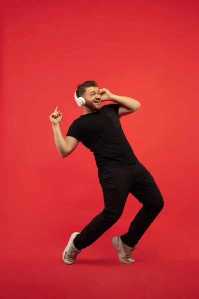 Full length portrait of young successfull high jumping man gesturing isolated on red studio background — 스톡 사진