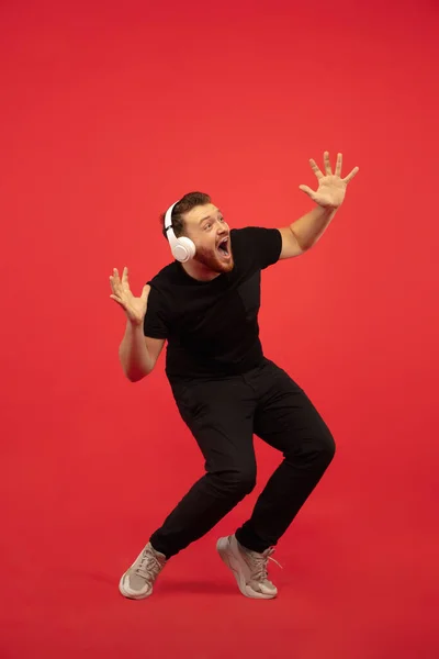 Portrait complet de jeune homme sautant en hauteur réussi gesticulant isolé sur fond de studio rouge — Photo