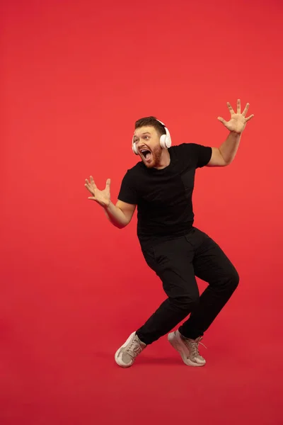 Portrait complet de jeune homme sautant en hauteur réussi gesticulant isolé sur fond de studio rouge — Photo
