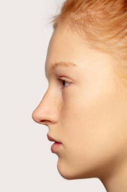 Stüdyo arka planında izole edilmiş güzel kızıl saçlı beyaz kız portresi. Güzellik, moda, cilt bakımı, kozmetik konsepti. Ayrıntılar.