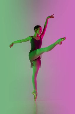 Genç ve zarif bale dansçıları, neon ışıklarıyla izole edilmiş pembe-yeşil stüdyo arka planına sahipler. Hareket halindeki sanat