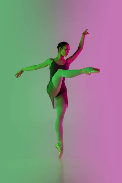Dançarina de balé jovem e graciosa isolada no fundo do estúdio gradiente rosa-verde em luz de néon. Arte em movimento — Fotografia de Stock