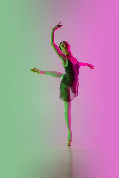 Joven y elegante bailarina de ballet aislada en el fondo del estudio de color rosa verdoso degradado en luz de neón. Arte en movimiento — Foto de Stock