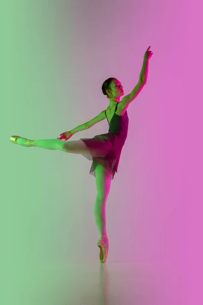 Νεαρή και χαριτωμένη χορεύτρια μπαλέτου απομονωμένη σε διαβαθμίσεις ροζ-πράσινο φόντο στούντιο σε νέον φως. Η τέχνη σε κίνηση — Φωτογραφία Αρχείου