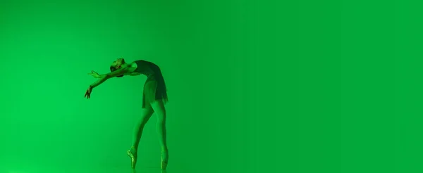 Joven y elegante bailarina de ballet aislada sobre fondo de estudio verde degradado en luz de neón. Arte en movimiento — Foto de Stock