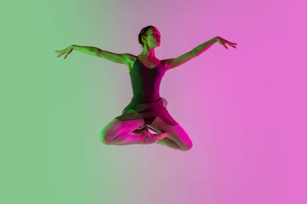 Genç ve zarif bale dansçıları, neon ışıklarıyla izole edilmiş pembe-yeşil stüdyo arka planına sahipler. Hareket halindeki sanat — Stok fotoğraf