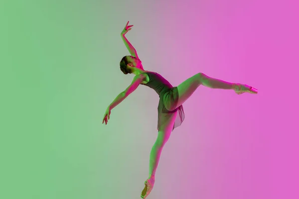 Giovane e graziosa ballerina isolata su uno sfondo rosa-verde sfumato da studio in luce al neon. Arte in movimento — Foto Stock