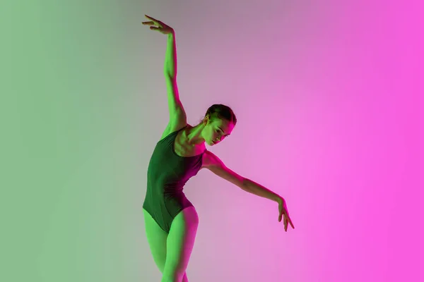 在霓虹灯下，年轻而优雅的芭蕾舞演员被隔离在渐变的粉色绿色工作室背景中。运动中的艺术 — 图库照片