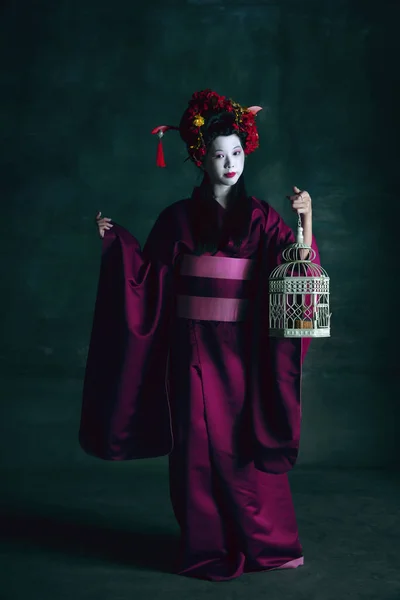 Ung japansk kvinna som geisha på mörkgrön bakgrund. Retrostil, jämförelse av tidsepoker koncept. — Stockfoto