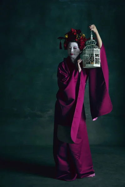Joven mujer japonesa como geisha sobre fondo verde oscuro. Estilo retro, comparación de conceptos de eras. — Foto de Stock