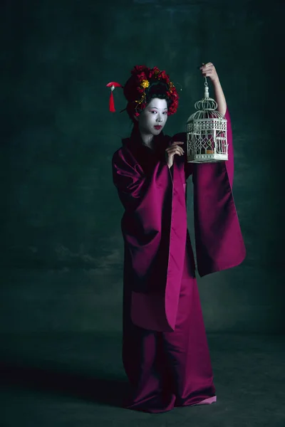 Joven mujer japonesa como geisha sobre fondo verde oscuro. Estilo retro, comparación de conceptos de eras. — Foto de Stock