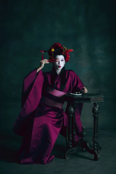Jovem mulher japonesa como gueixa no fundo verde escuro. Estilo retro, comparação do conceito eras. — Fotografia de Stock