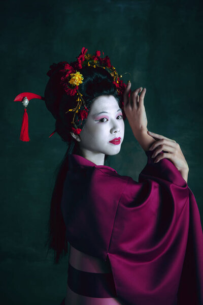 Young japanese woman as geisha on dark green background. Retro style, comparison of eras concept.