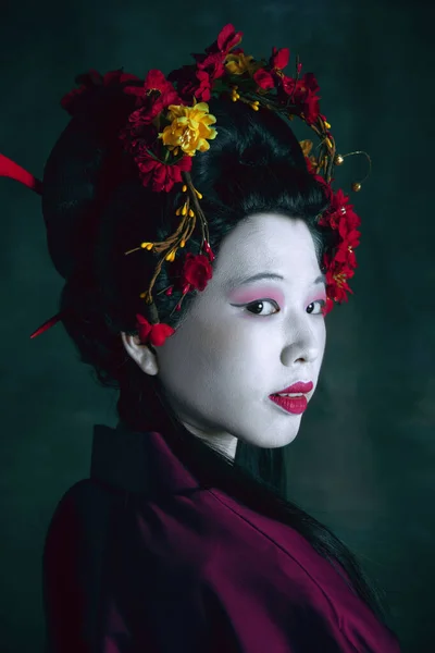 Jeune femme japonaise comme geisha sur fond vert foncé. Style rétro, comparaison des époques concept. — Photo