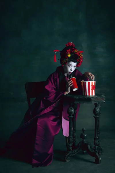 Ung japansk kvinna som geisha på mörkgrön bakgrund. Retrostil, jämförelse av tidsepoker koncept. — Stockfoto