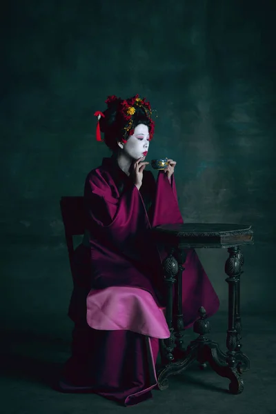 Young japanese woman as geisha on dark green background. Retro style, comparison of eras concept. — Stock Photo, Image