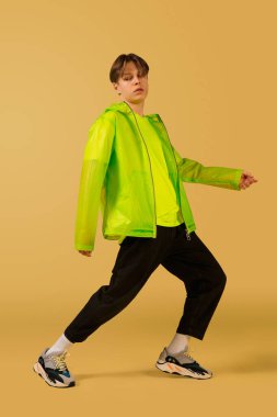 Sarı arka planda yalnız dans eden eski moda genç adam.