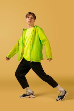 Sarı arka planda yalnız dans eden eski moda genç adam.