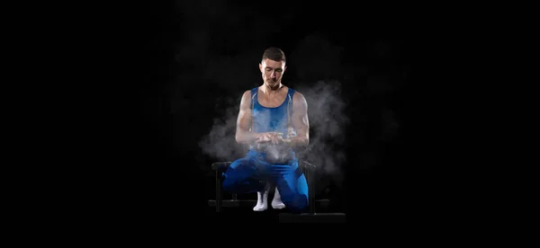 Entrenamiento muscular masculino de gimnasta en gimnasio, flexible y activo. Caucásico chico en forma, atleta en ropa deportiva azul aislado en negro — Foto de Stock