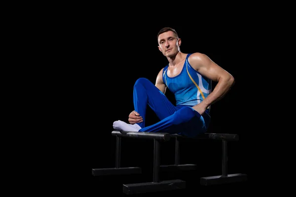 Musculaire mannelijke gymnastiektraining in de sportschool, flexibel en actief. Blanke fit man, atleet in blauwe sportkleding geïsoleerd op zwart — Stockfoto