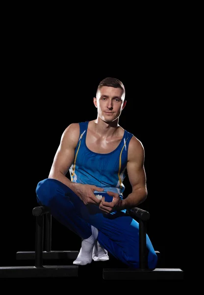 Мышечная мужская гимнастика в тренажерном зале, гибкая и активная. Белый парень, спортсмен в синей спортивной одежде, изолированный на черном — стоковое фото