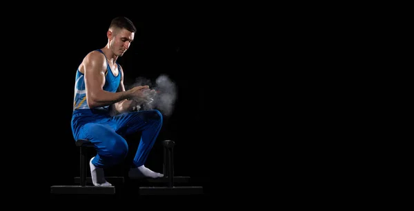 Entrenamiento muscular masculino de gimnasta en gimnasio, flexible y activo. Caucásico chico en forma, atleta en ropa deportiva azul aislado en negro — Foto de Stock